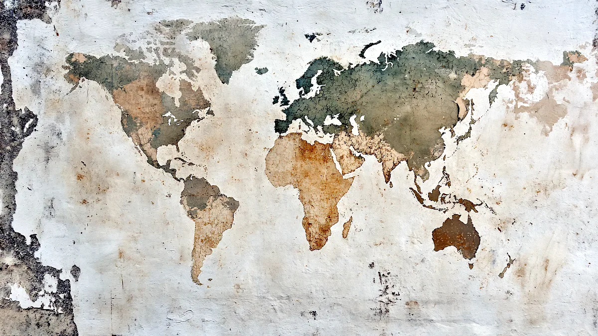 A faded world map pinned to a plaster wall, creases running through the ocean.
