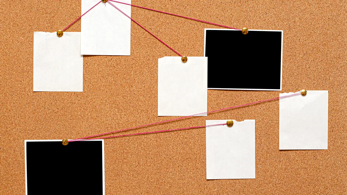 A wall covered in pinned notes, printouts and small photos, the pins clustered thickest near the centre.