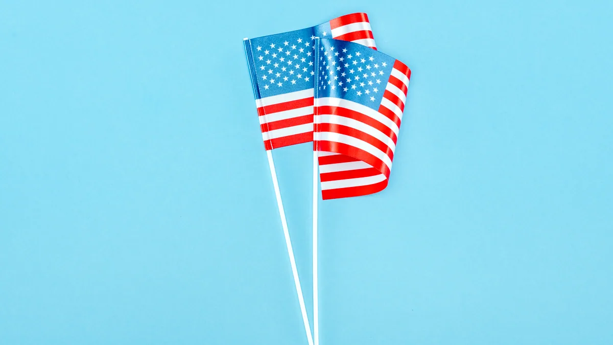 Two small flags on short poles, both bending the same way in the wind.