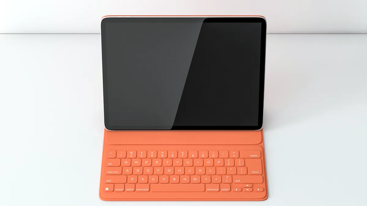 A slate grey tablet tucked into a hinged keyboard cover, sitting on a desk mat.