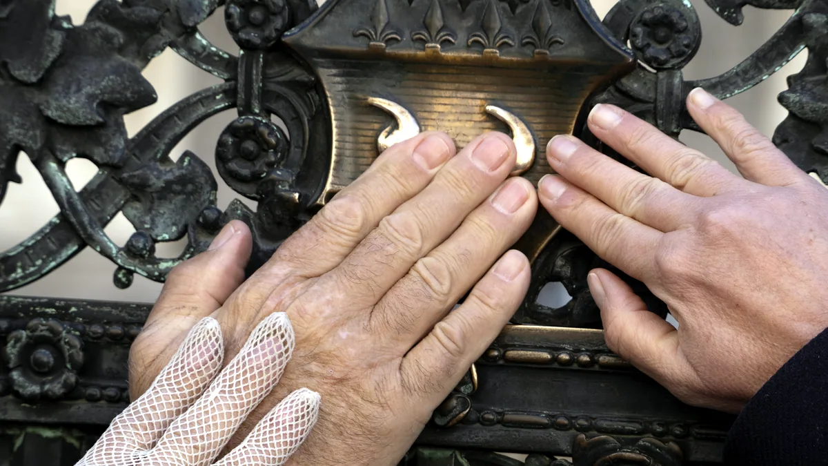 Fingers fitting two worn mechanical parts together, a small screwdriver resting nearby.