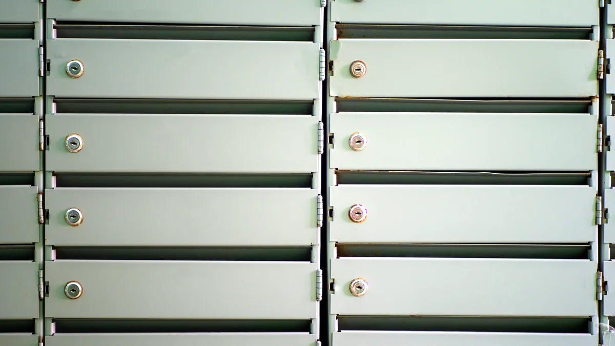 Tall shelves of metal filing cabinets in a dim room, one drawer left hanging open.