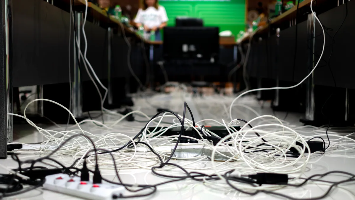 A tangled bundle of network cables on a desk, one plug dangling toward a port.