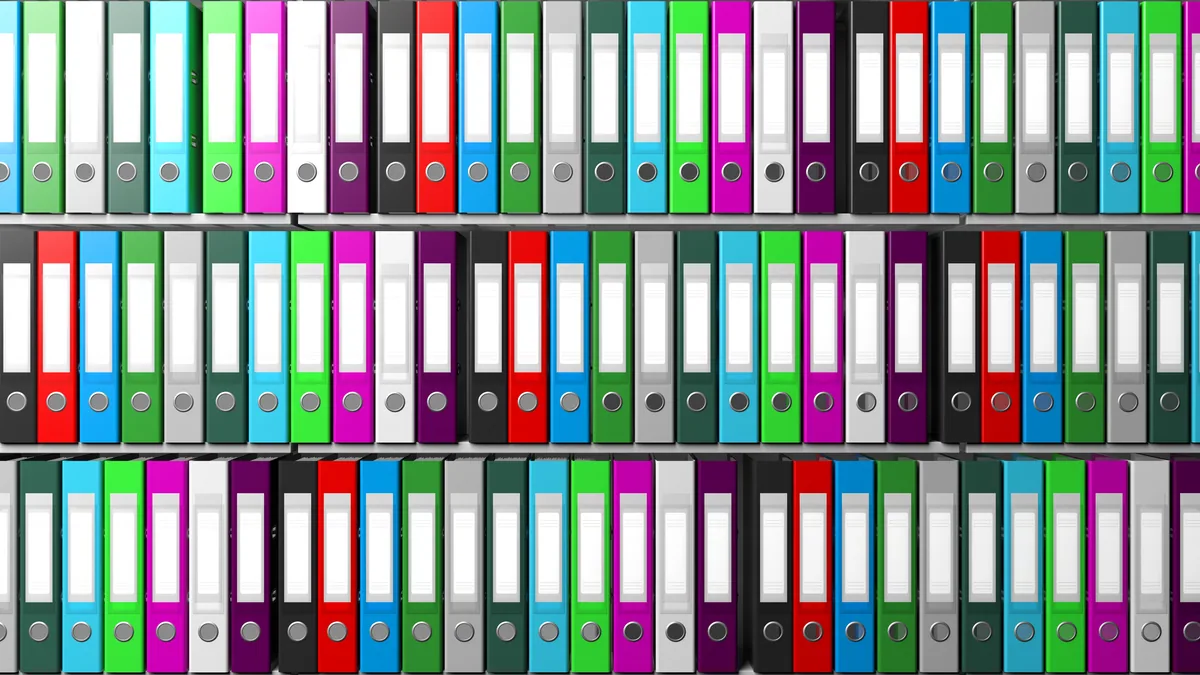 A row of numbered file folders on a shelf, the newest one with a blank white label.
